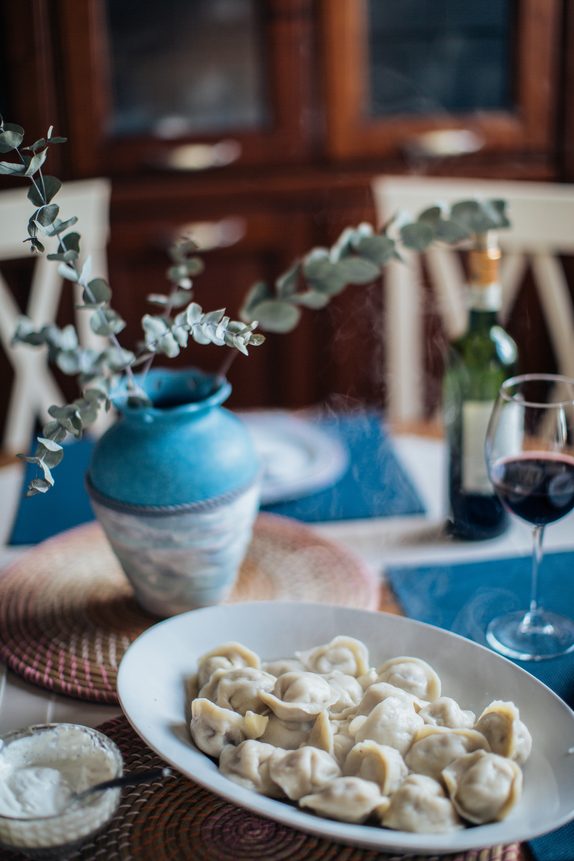 Plate of Pelmeni on Table Next to Flower Vase