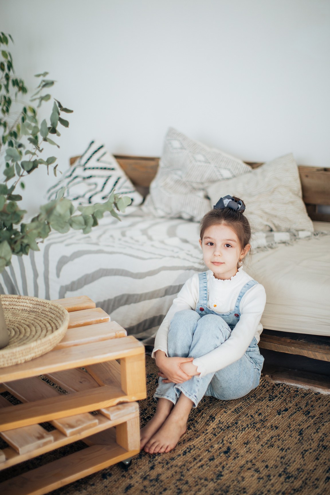 Girl in Blue Dress Shirt and Blue Denim Jeans Sitting on Brown Wooden Coffee Table